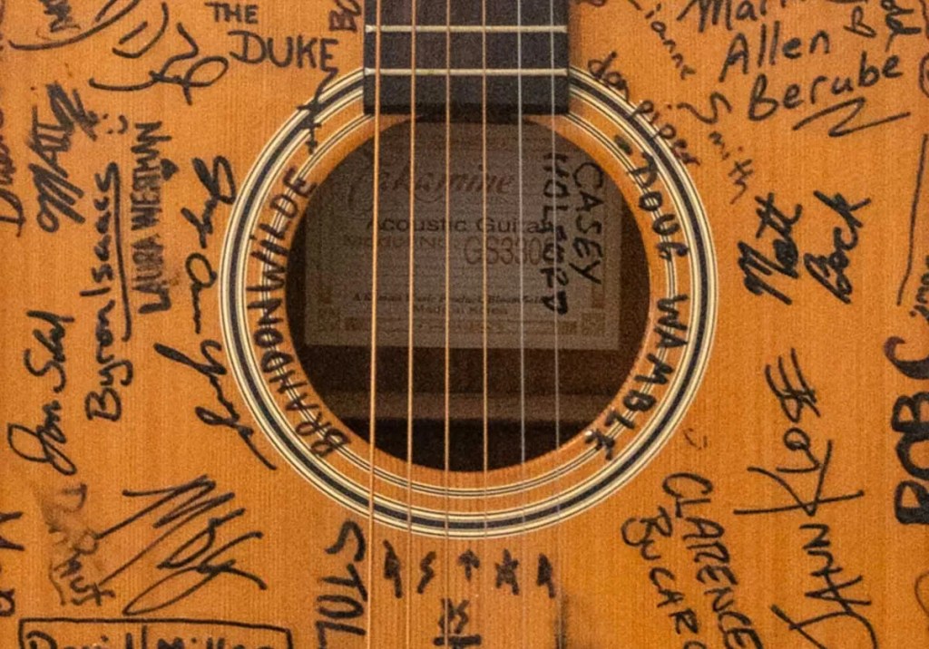 Artist signatures surround the soundhole of the New York Acoustic Guitar Project Takamine